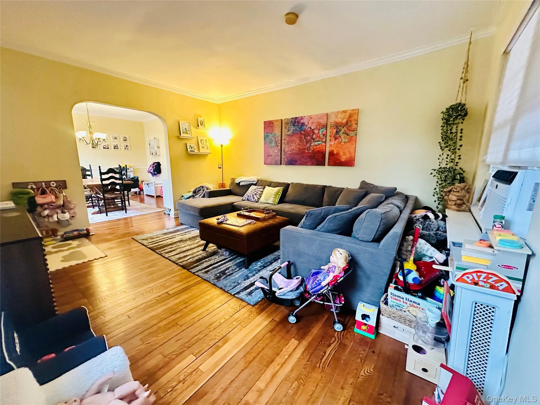 Living area with arched walkways, ornamental molding, hardwood / wood-style flooring, a chandelier, and cooling unit Living area with arched walkways, ornamental molding, hardwood / wood-style flooring, a chandelier, and cooling unit