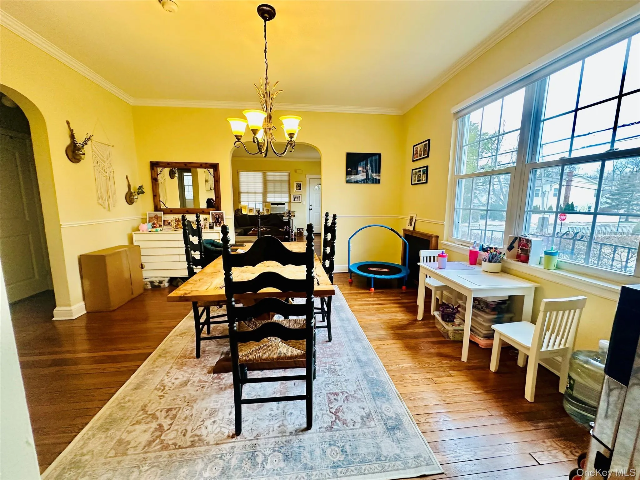 Dining area with arched walkways, hardwood / wood-style flooring, crown molding, and a chandelier Dining area with arched walkways, hardwood / wood-style flooring, crown molding, and a chandelier