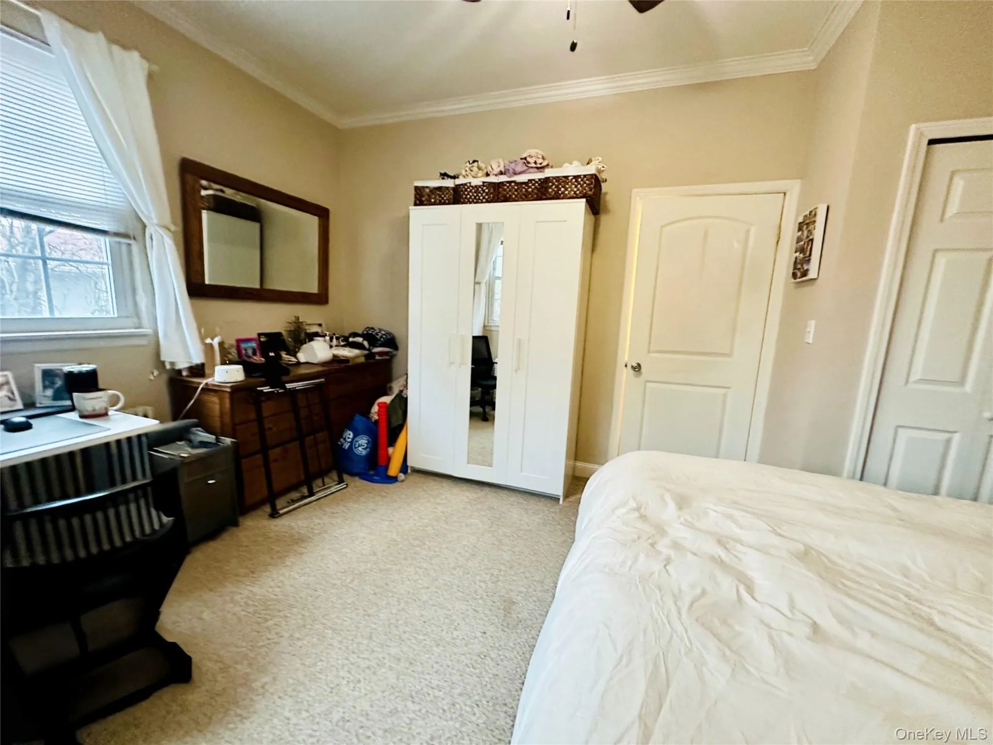 Bedroom with ornamental molding, ceiling fan, and light carpet Bedroom with ornamental molding, ceiling fan, and light carpet