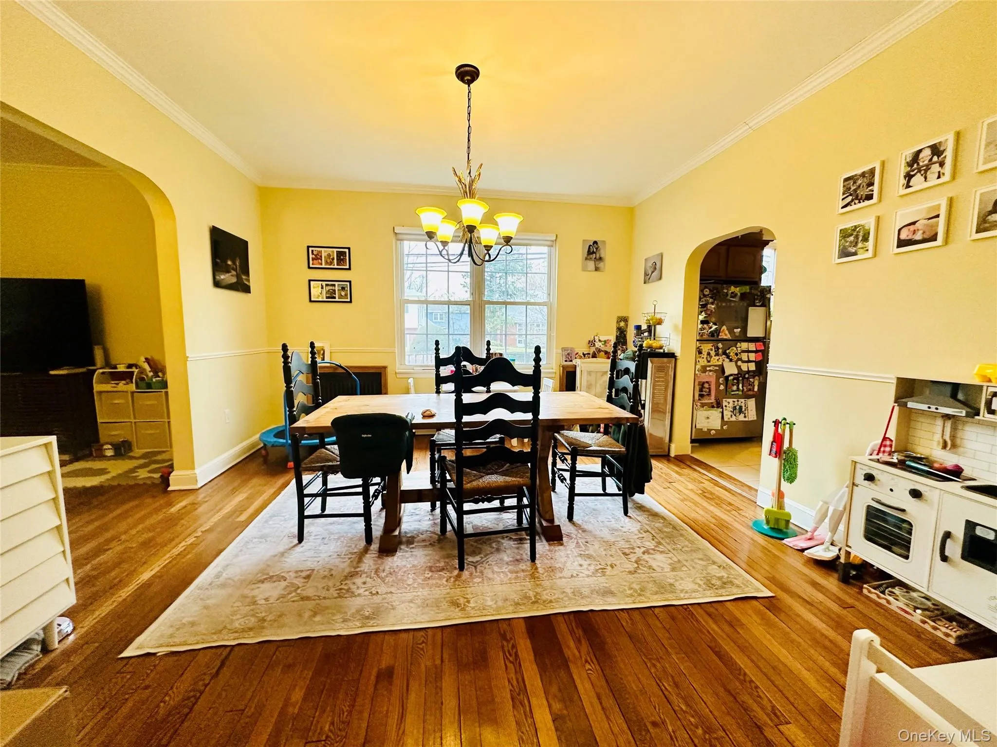 Dining room featuring arched walkways, light wood finished floors, ornamental molding, and a chandelier Dining room featuring arched walkways, light wood finished floors, ornamental molding, and a chandelier