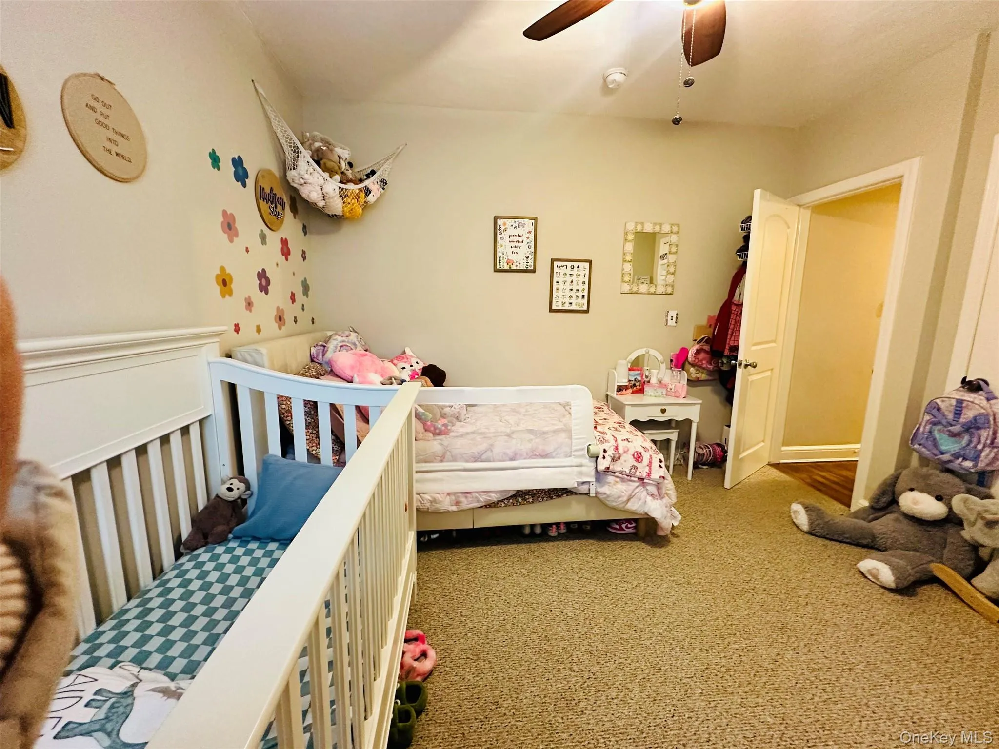 Carpeted bedroom featuring a crib and a ceiling fan Carpeted bedroom featuring a crib and a ceiling fan