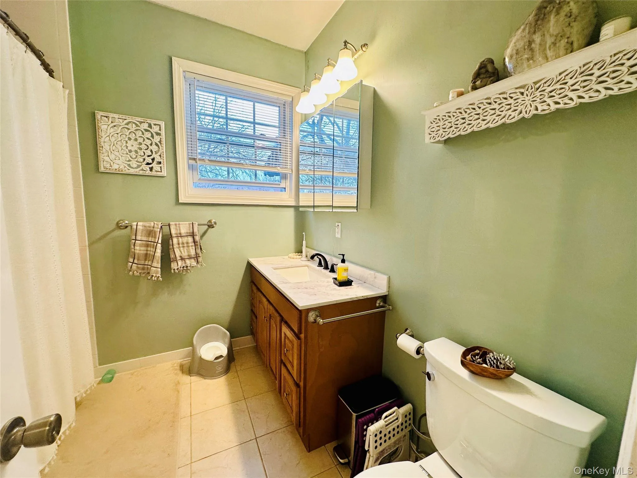 Full bath featuring a shower with curtain, vanity, and light tile patterned floors Full bath featuring a shower with curtain, vanity, and light tile patterned floors