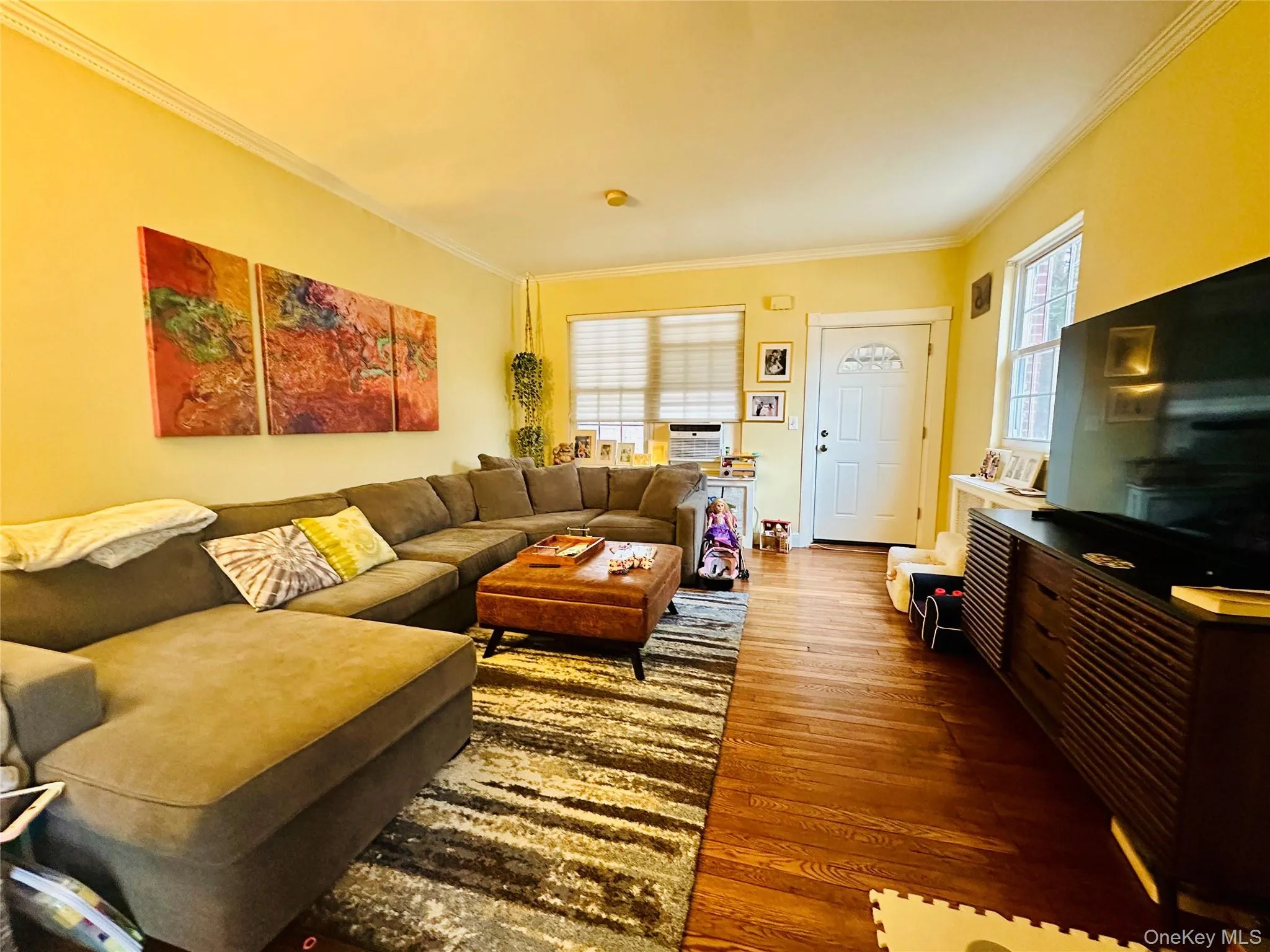 Living room with crown molding and wood finished floors Living room with crown molding and wood finished floors