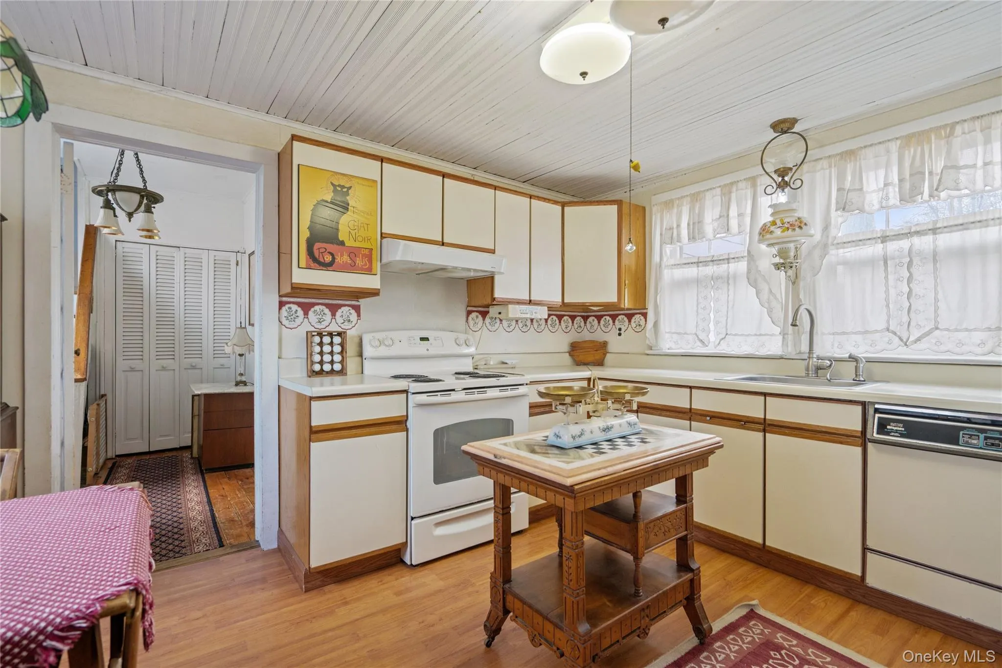 Kitchen featuring white appliances, light countertops, decorative light fixtures, and under cabinet range hood Kitchen featuring white appliances, light countertops, decorative light fixtures, and under cabinet range hood