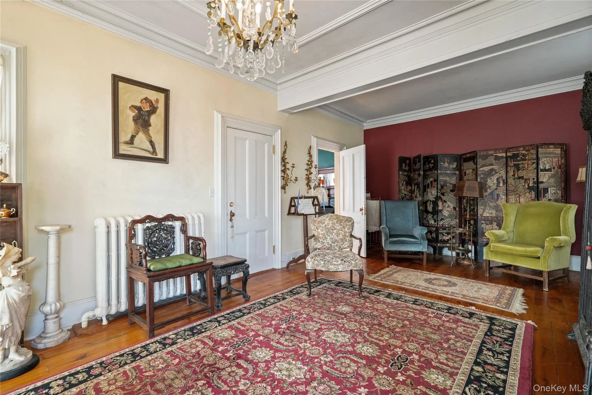 Sitting room with radiator, hardwood / wood-style flooring, ornamental molding, and a chandelier Sitting room with radiator, hardwood / wood-style flooring, ornamental molding, and a chandelier