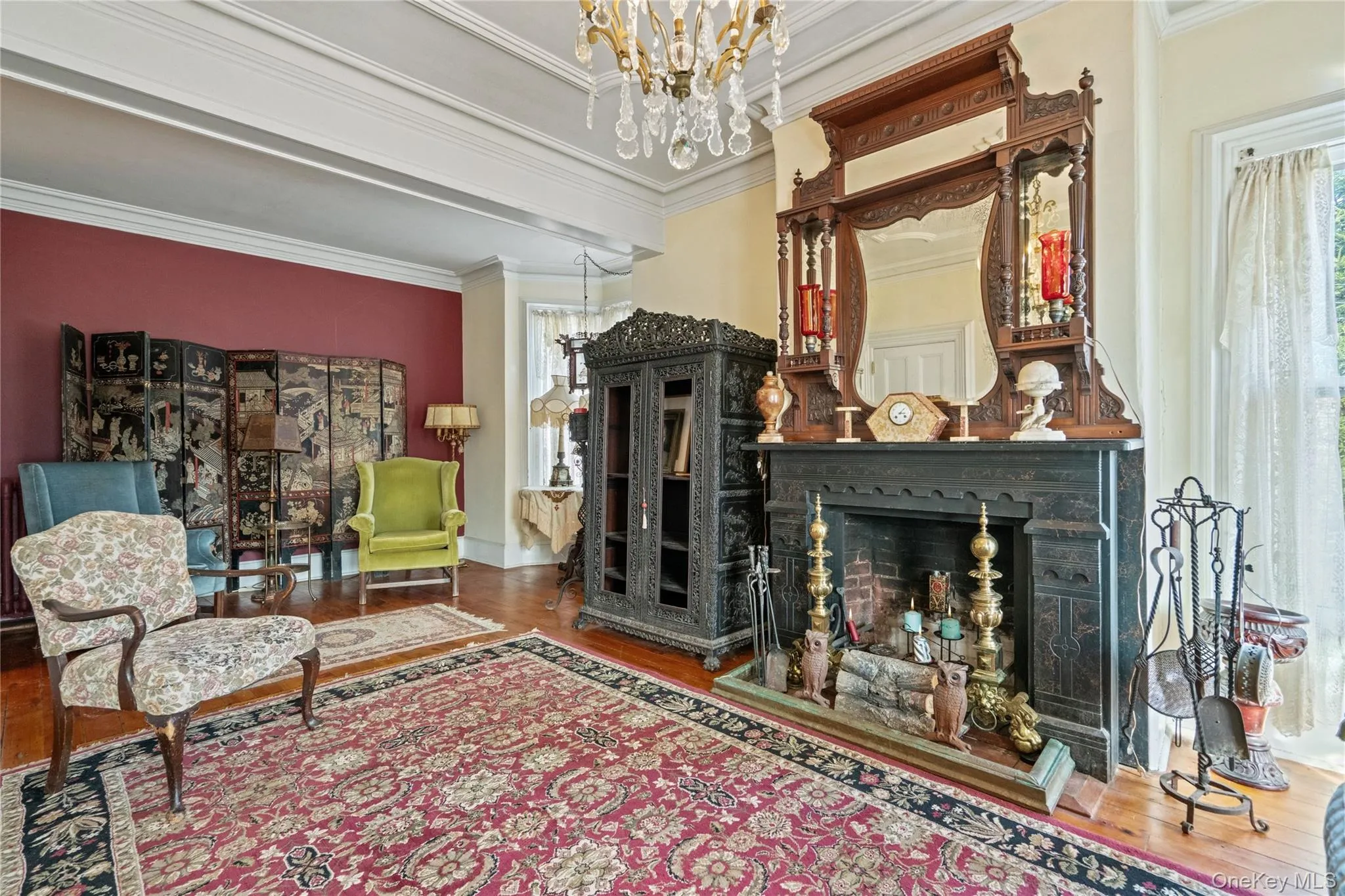 Living area featuring a fireplace, a chandelier, crown molding, and wood finished floors Living area featuring a fireplace, a chandelier, crown molding, and wood finished floors
