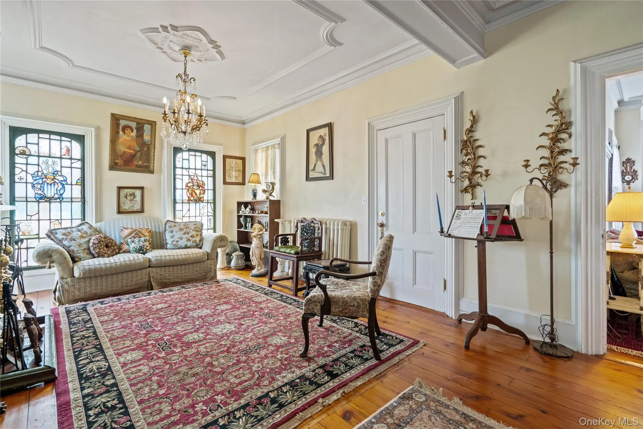 Living area with hardwood / wood-style flooring, a chandelier, ornamental molding, and radiator Living area with hardwood / wood-style flooring, a chandelier, ornamental molding, and radiator