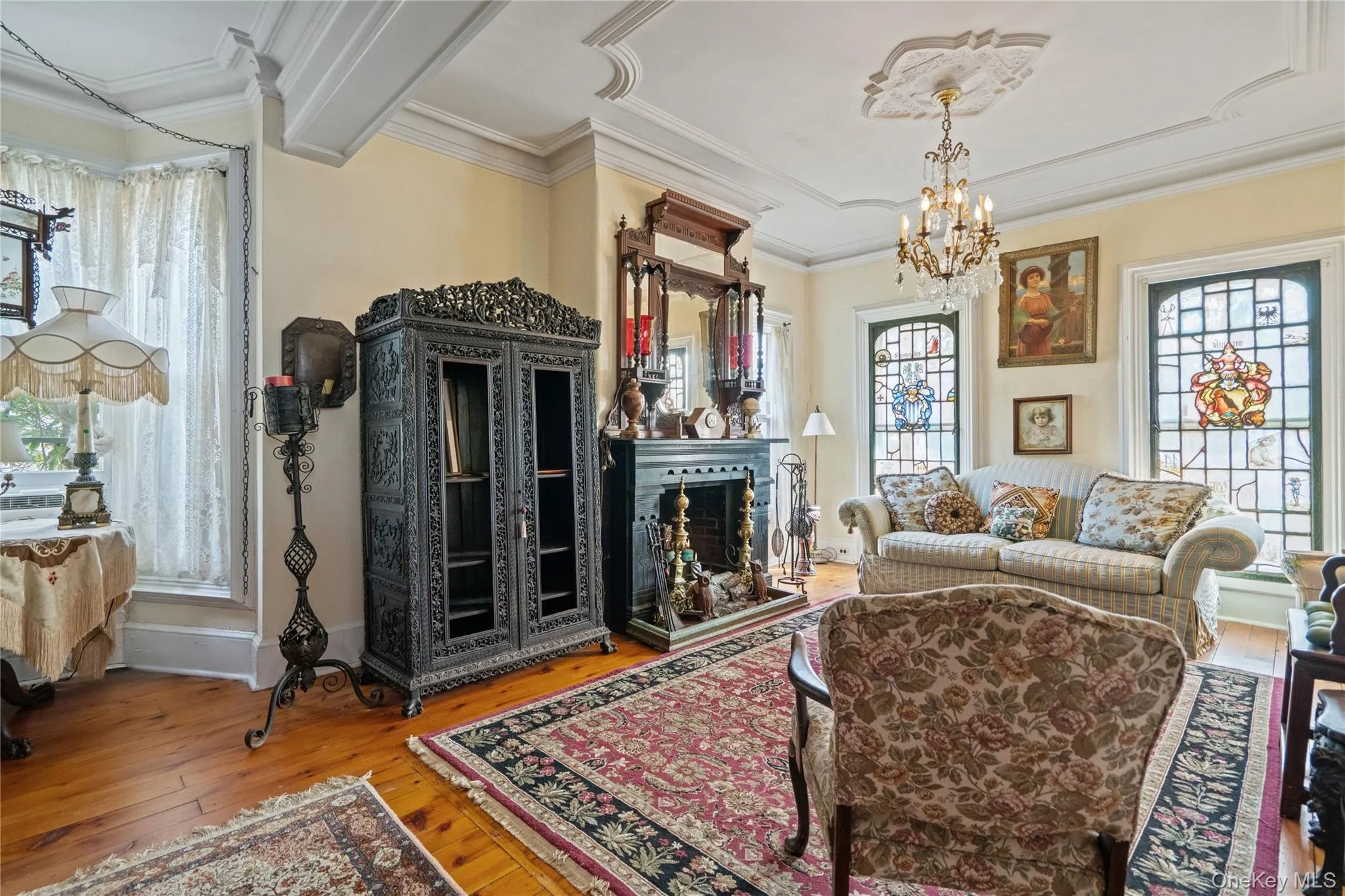 Living room featuring plenty of natural light, a chandelier, a fireplace with raised hearth, wood-type flooring, and ornamental molding Living room featuring plenty of natural light, a chandelier, a fireplace with raised hearth, wood-type flooring, and ornamental molding