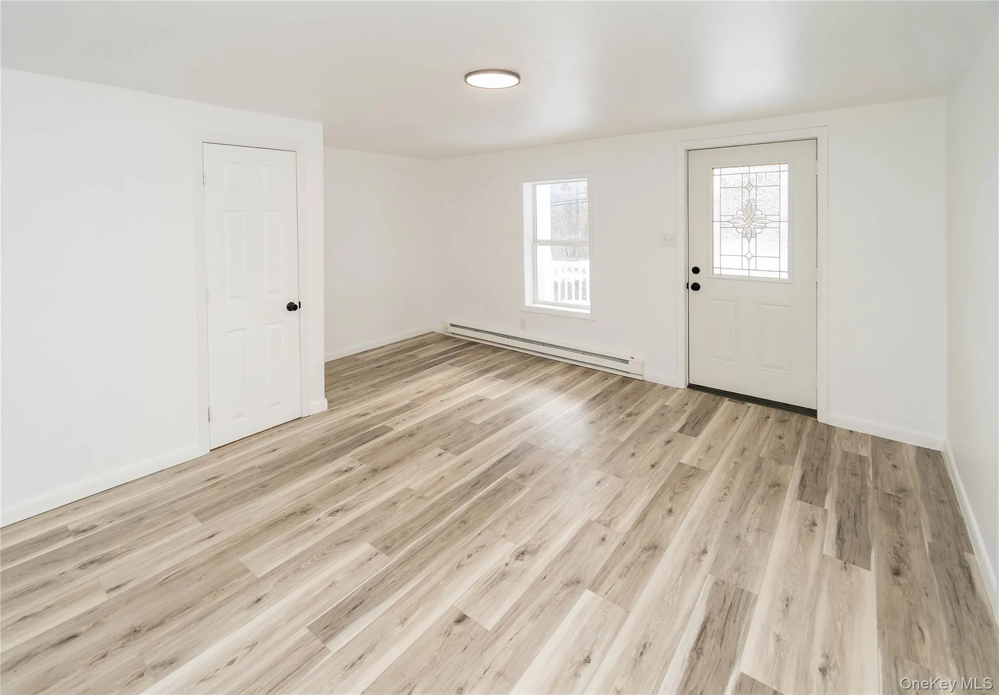 Entryway featuring light wood finished floors and a baseboard heating unit Entryway featuring light wood finished floors and a baseboard heating unit