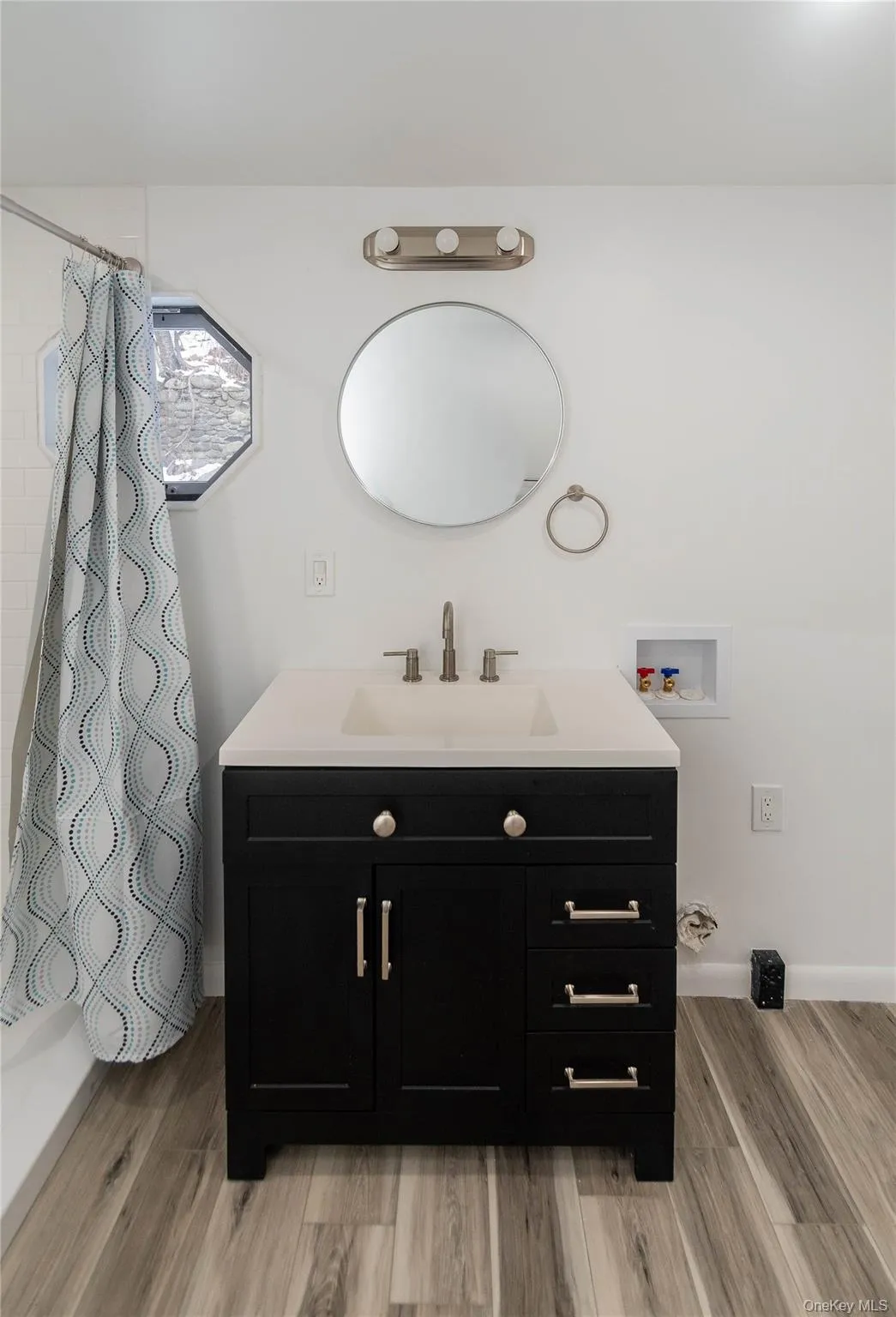 Bathroom featuring vanity, curtained shower, and light wood finished floors Bathroom featuring vanity, curtained shower, and light wood finished floors