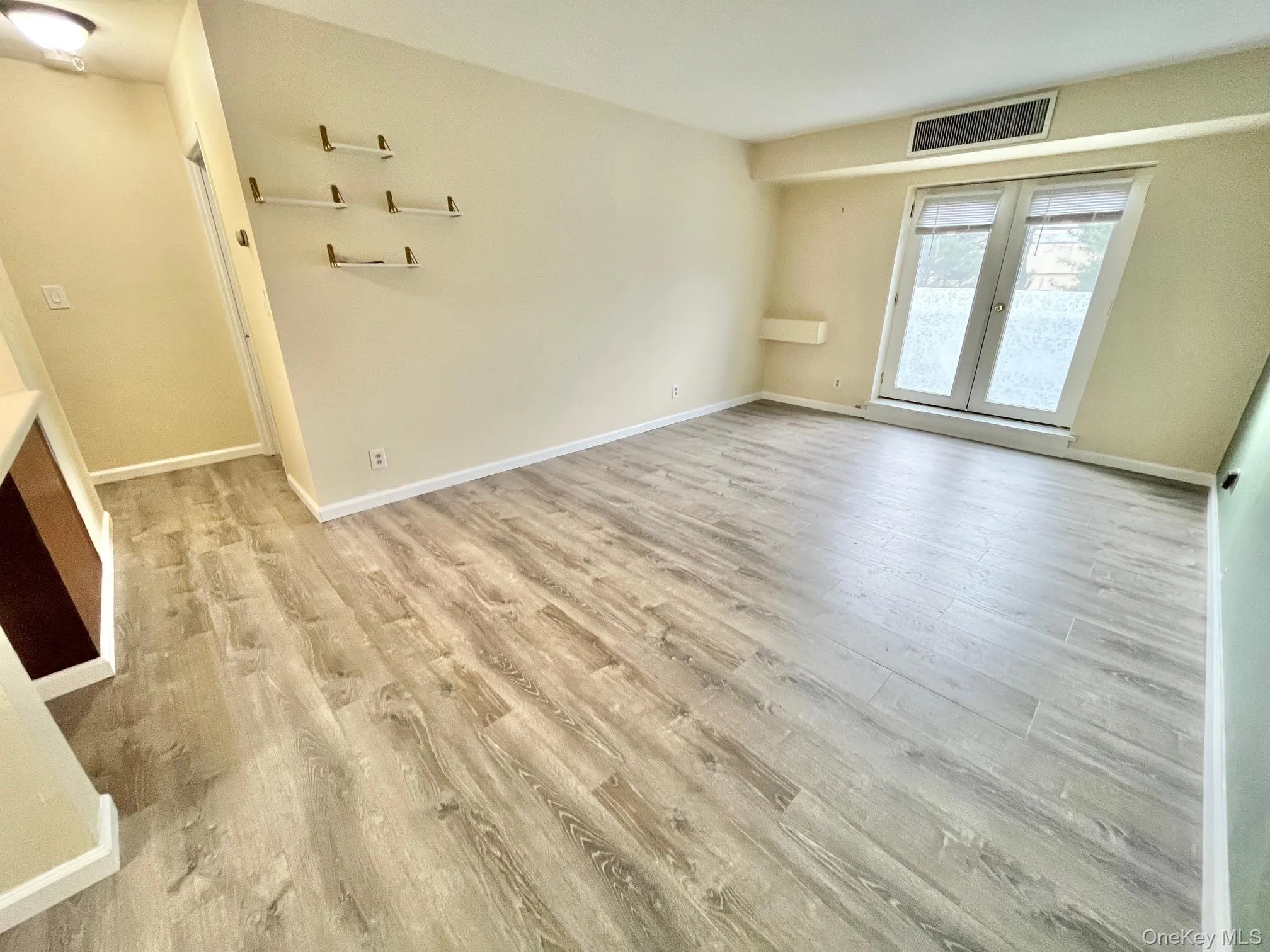 Spare room with light wood finished floors and french doors Spare room with light wood finished floors and french doors