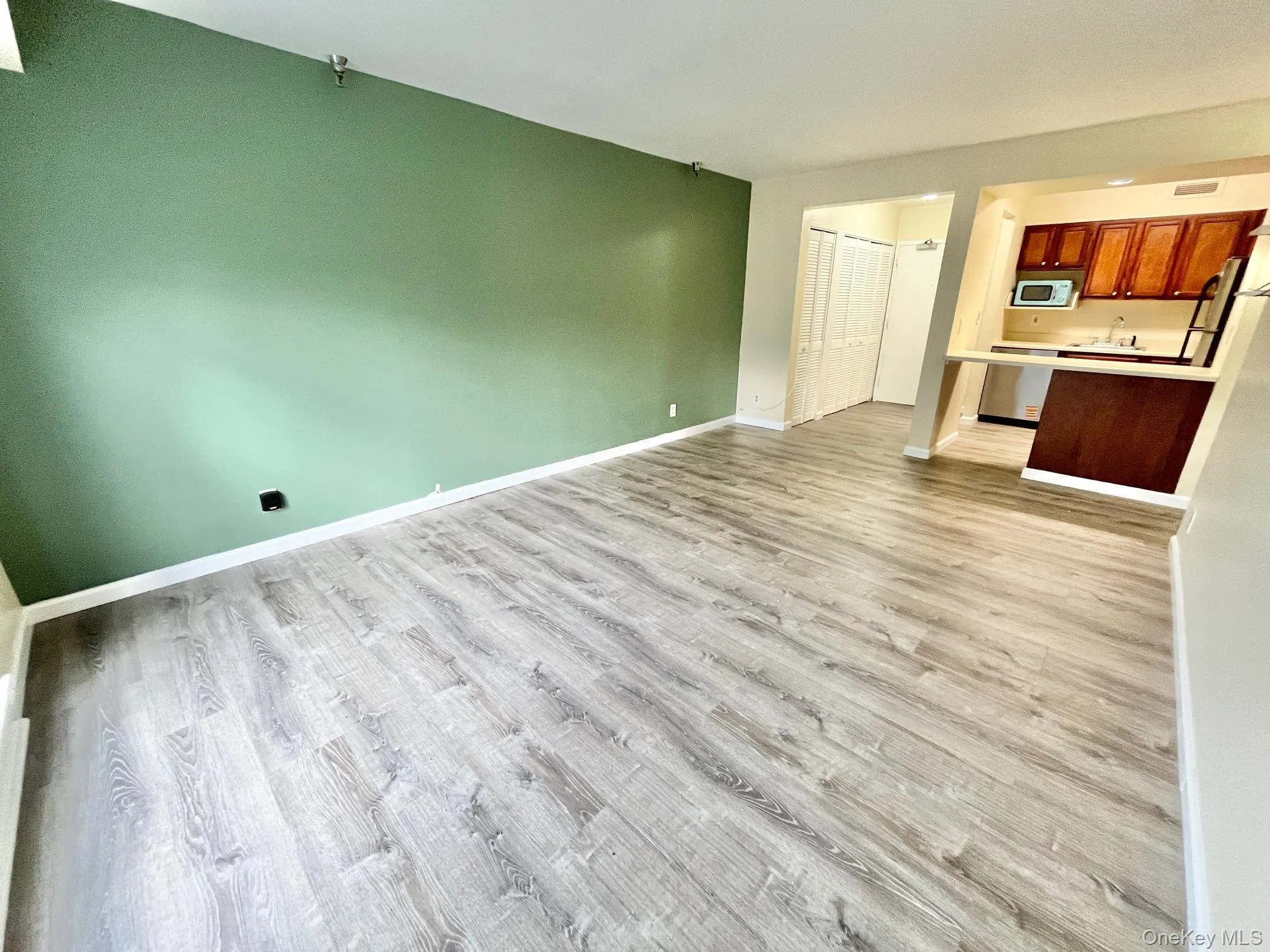 Unfurnished living room with light wood-style flooring and baseboards Unfurnished living room with light wood-style flooring and baseboards