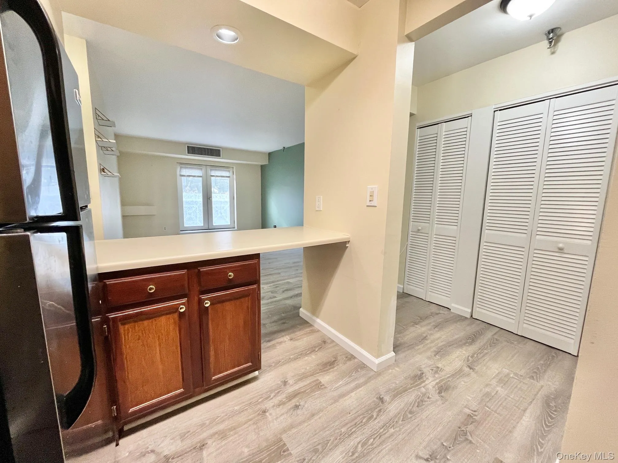 Kitchen featuring freestanding refrigerator, light countertops, light vinyl flooring, and a peninsula. Kitchen featuring freestanding refrigerator, light countertops, light vinyl flooring, and a peninsula.