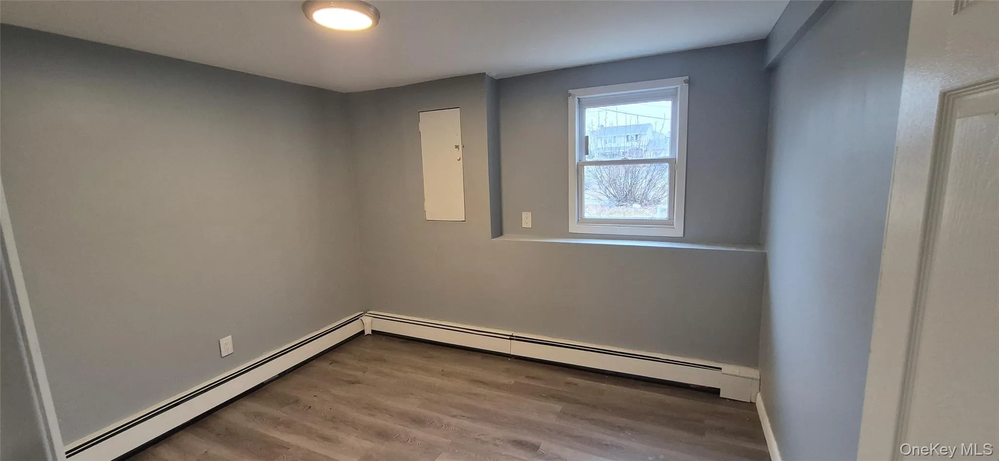 Unfurnished room featuring a baseboard heating unit and light wood-style floors Unfurnished room featuring a baseboard heating unit and light wood-style floors