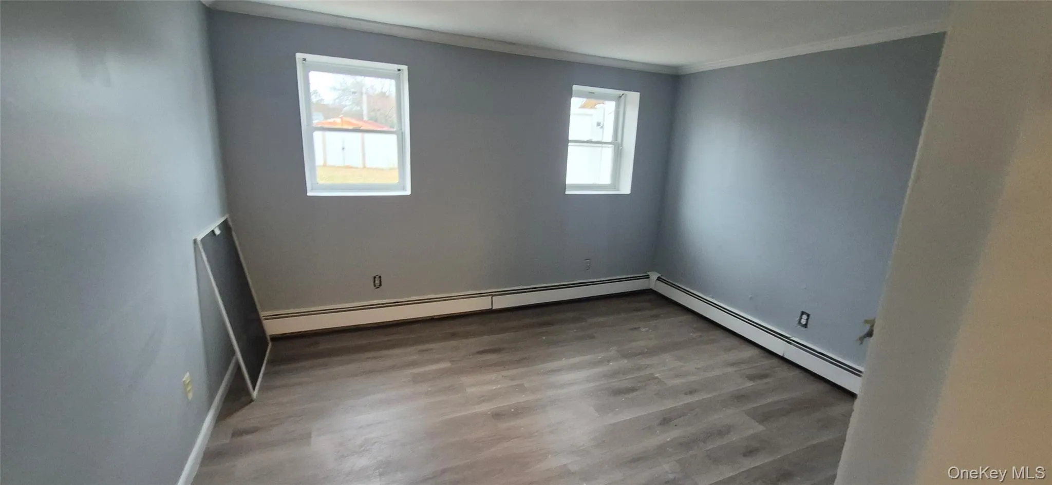 Unfurnished room with ornamental molding, a baseboard radiator, and light wood-style flooring Unfurnished room with ornamental molding, a baseboard radiator, and light wood-style flooring