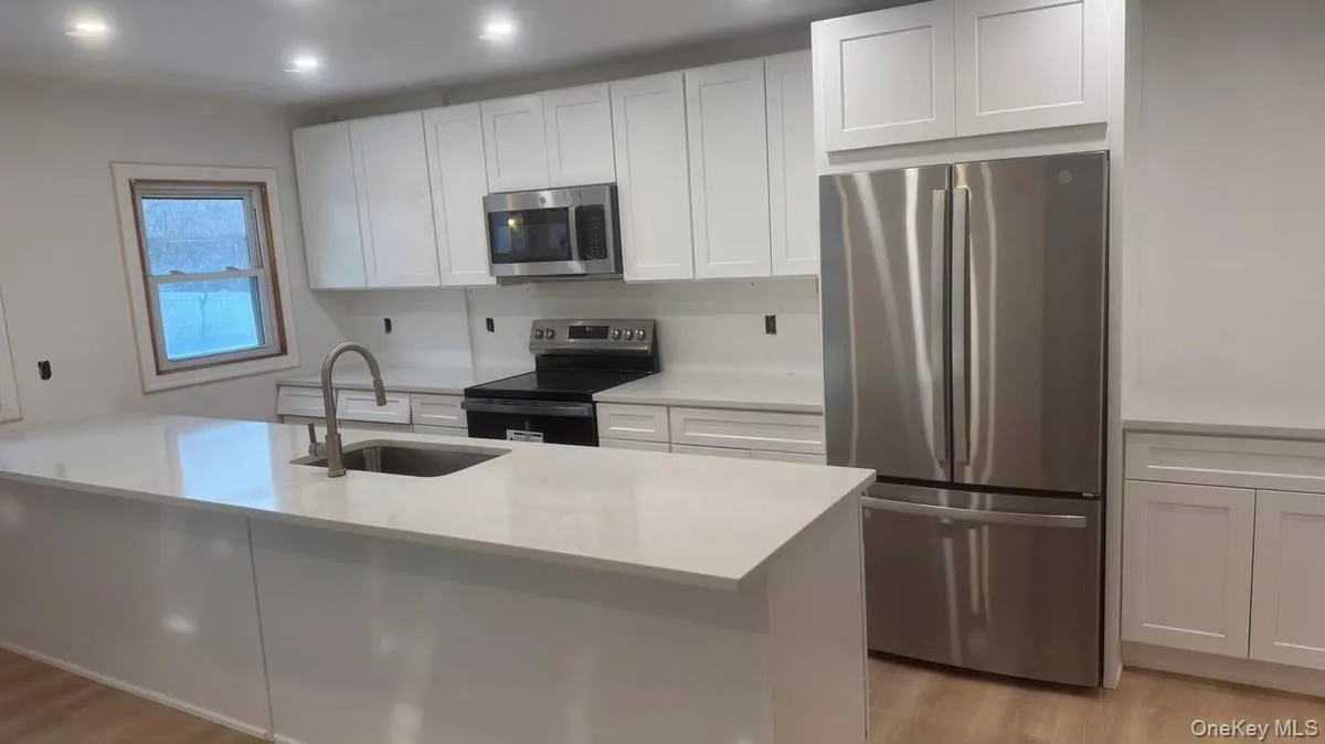 Kitchen with stainless steel appliances, white cabinetry, light wood-type flooring, a peninsula, and recessed lighting Kitchen with stainless steel appliances, white cabinetry, light wood-type flooring, a peninsula, and recessed lighting