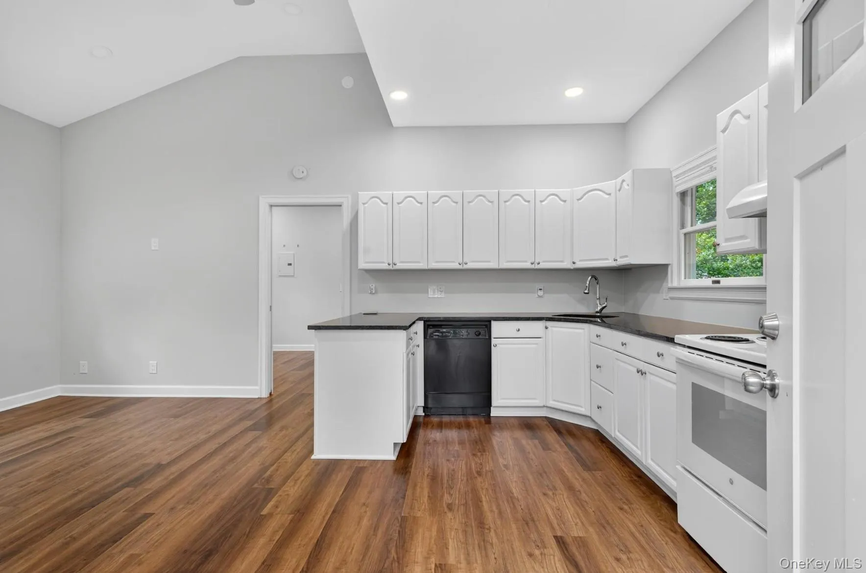 Kitchen featuring electric range, black dishwasher, a peninsula, white cabinets, and vaulted ceiling Kitchen featuring electric range, black dishwasher, a peninsula, white cabinets, and vaulted ceiling