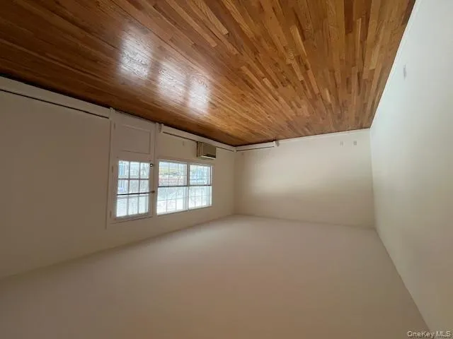 Empty room with light wood finished floors, a wall mounted air conditioner, and baseboard heating Empty room with light wood finished floors, a wall mounted air conditioner, and baseboard heating