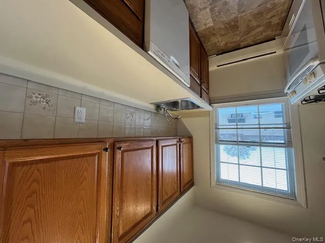 Kitchen featuring tasteful backsplash, a baseboard radiator, dishwasher, light countertops, and stove Kitchen featuring tasteful backsplash, a baseboard radiator, dishwasher, light countertops, and stove
