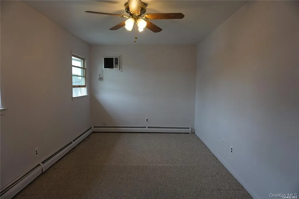 Empty room with a baseboard heating unit, carpet floors, and ceiling fan Empty room with a baseboard heating unit, carpet floors, and ceiling fan