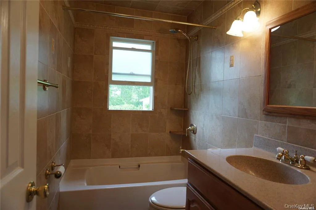 Full bathroom featuring vanity, washtub / shower combination, and tile walls Full bathroom featuring vanity, washtub / shower combination, and tile walls