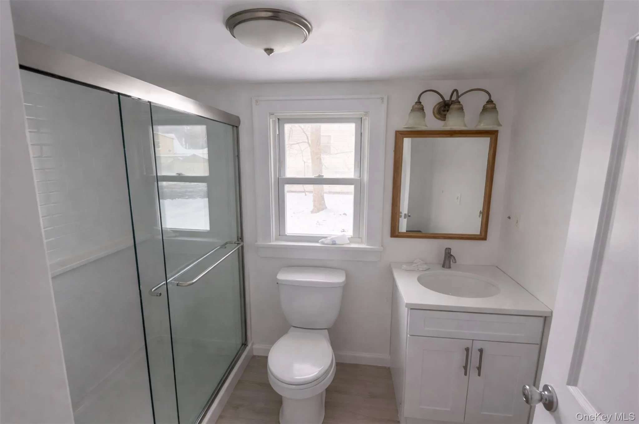 Bathroom with vanity, a shower stall, and light wood-type flooring Bathroom with vanity, a shower stall, and light wood-type flooring