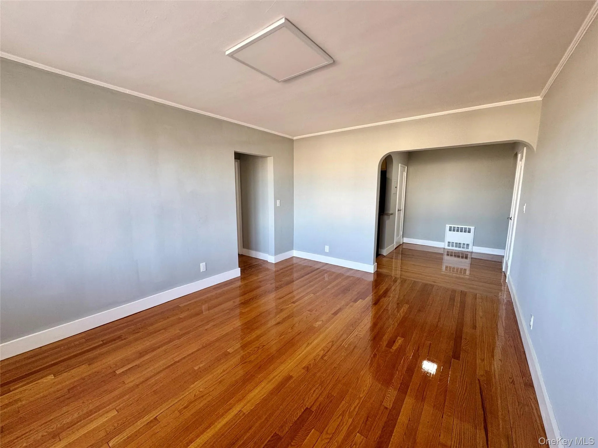 Unfurnished room with crown molding, radiator heating unit, and hardwood / wood-style flooring Unfurnished room with crown molding, radiator heating unit, and hardwood / wood-style flooring