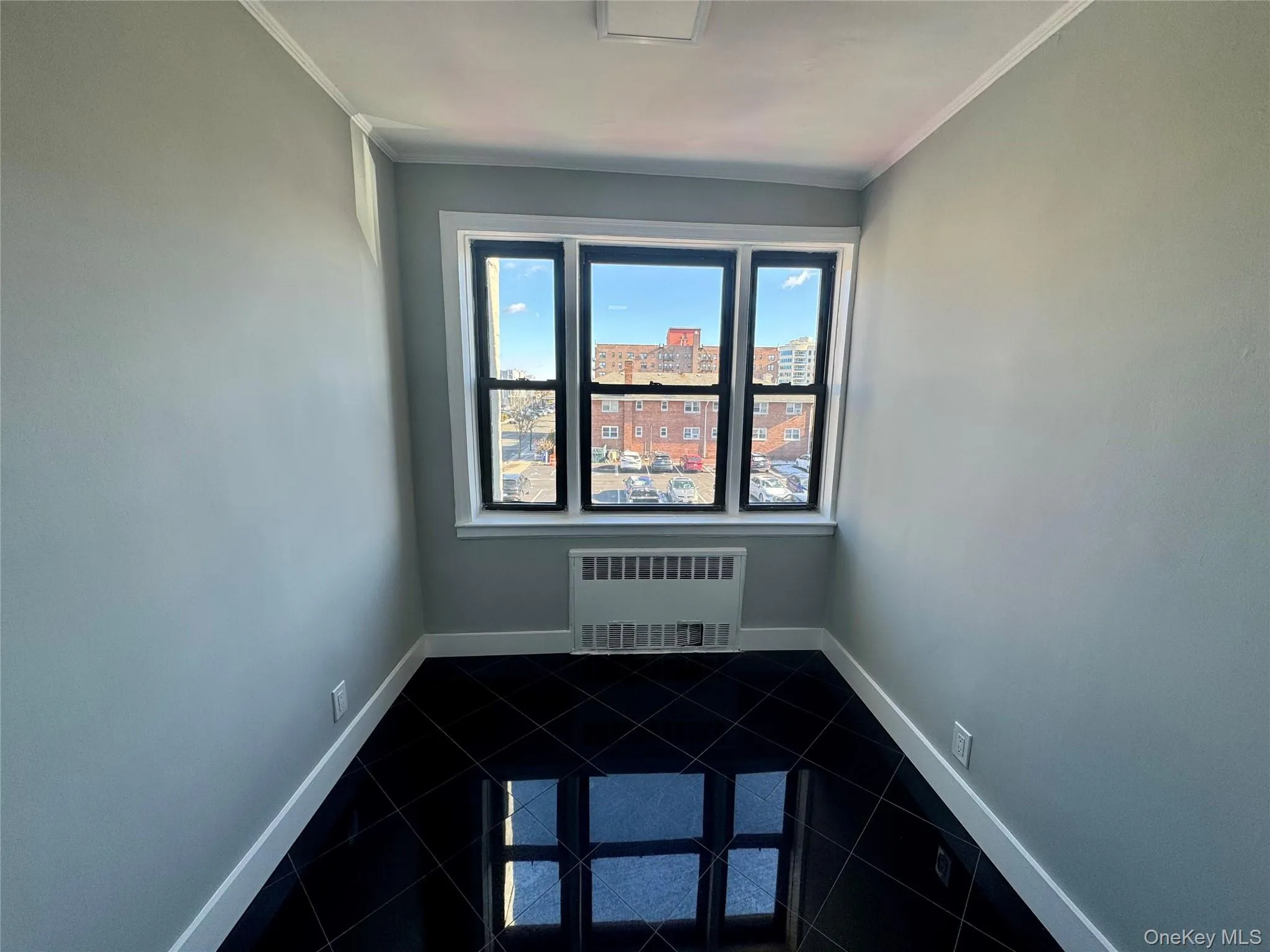 Tiled spare room featuring crown molding and radiator heating unit Tiled spare room featuring crown molding and radiator heating unit