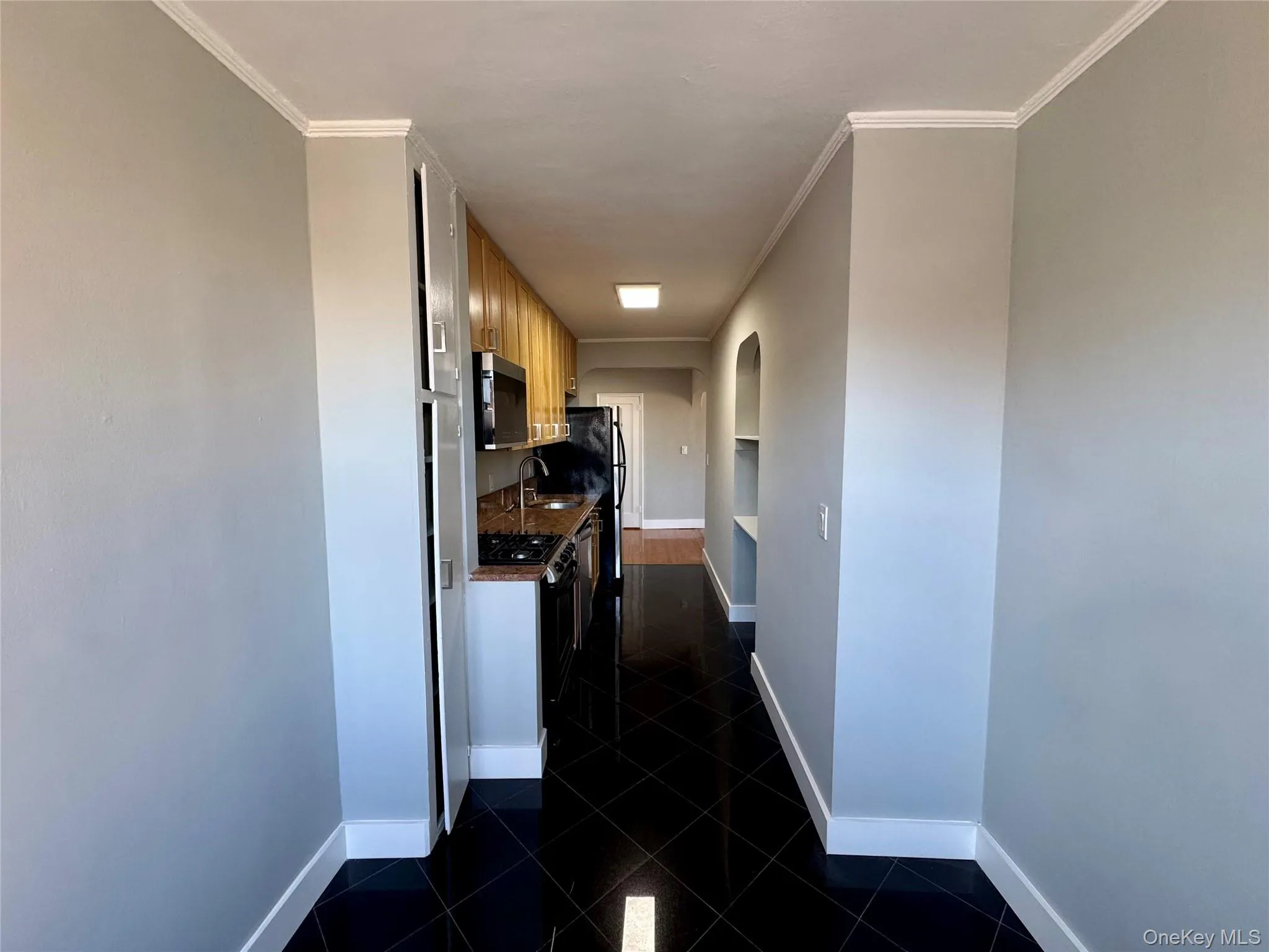 Hallway featuring built in features, ornamental molding, and sink Hallway featuring built in features, ornamental molding, and sink