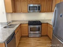 Kitchen with stainless steel appliances, brown cabinets, and light wood-style flooring Kitchen with stainless steel appliances, brown cabinets, and light wood-style flooring