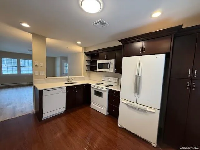 Kitchen with white appliances, light countertops, dark wood-style Cabinets, Updated flooring, open shelves, and recessed lighting Kitchen with white appliances, light countertops, dark wood-style Cabinets, Updated flooring, open shelves, and recessed lighting