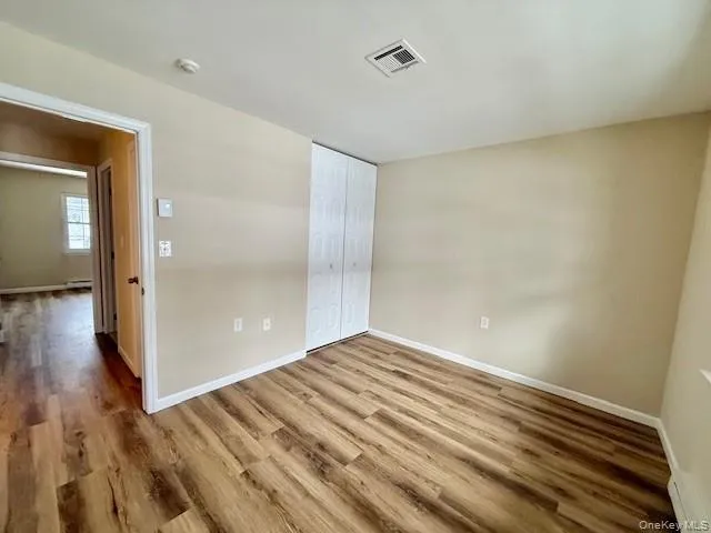 Unfurnished bedroom with New wood finished floors, a closet, and a baseboard radiator Unfurnished bedroom with New wood finished floors, a closet, and a baseboard radiator