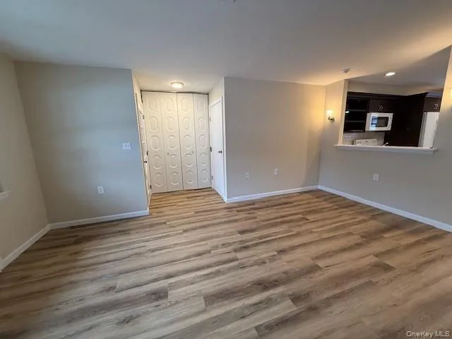 Unfurnished living room featuring new wood finished floors and baseboards Open to the Kitchen. Unfurnished living room featuring new wood finished floors and baseboards Open to the Kitchen.