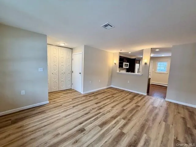 Unfurnished living room featuring new light wood-style floors and baseboard heating Plus Closet Unfurnished living room featuring new light wood-style floors and baseboard heating Plus Closet