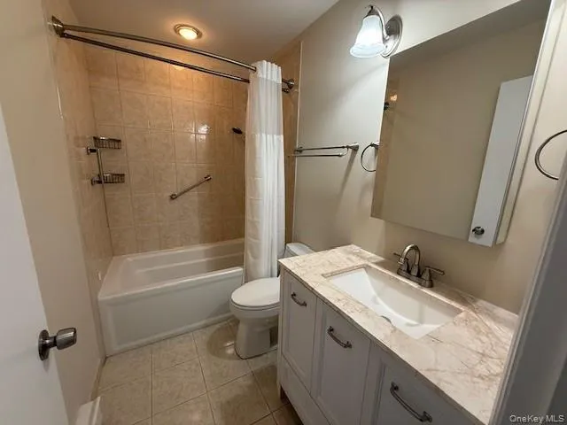 Bathroom featuring Updated vanity, shower / tub combo with curtain, and light tile patterned floors Bathroom featuring Updated vanity, shower / tub combo with curtain, and light tile patterned floors