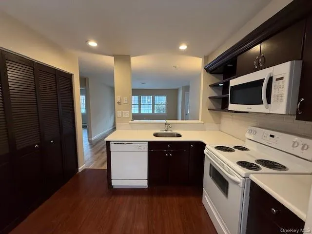 Kitchen featuring white appliances, light countertops, tasteful backsplash, dark wood-style floors, and open shelves Kitchen featuring white appliances, light countertops, tasteful backsplash, dark wood-style floors, and open shelves