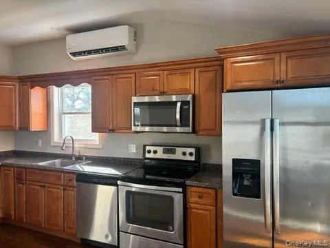 Kitchen with stainless steel appliances, brown cabinets, an AC wall unit, and vaulted ceiling Kitchen with stainless steel appliances, brown cabinets, an AC wall unit, and vaulted ceiling
