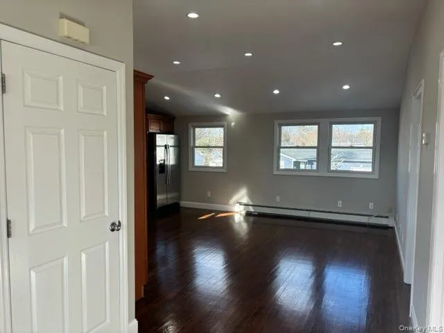 Spare room with baseboard heating, dark wood finished floors, vaulted ceiling, and recessed lighting Spare room with baseboard heating, dark wood finished floors, vaulted ceiling, and recessed lighting