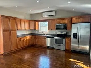 Kitchen featuring brown cabinets, appliances with stainless steel finishes, dark countertops, dark wood-type flooring, and recessed lighting Kitchen featuring brown cabinets, appliances with stainless steel finishes, dark countertops, dark wood-type flooring, and recessed lighting
