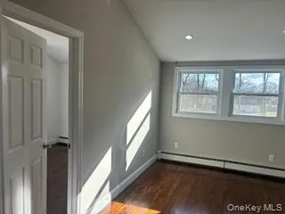 Spare room featuring dark wood-style flooring, a baseboard radiator, and recessed lighting Spare room featuring dark wood-style flooring, a baseboard radiator, and recessed lighting