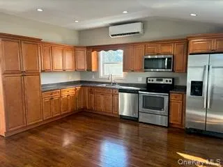 Kitchen featuring brown cabinetry, stainless steel appliances, dark countertops, recessed lighting, and vaulted ceiling Kitchen featuring brown cabinetry, stainless steel appliances, dark countertops, recessed lighting, and vaulted ceiling