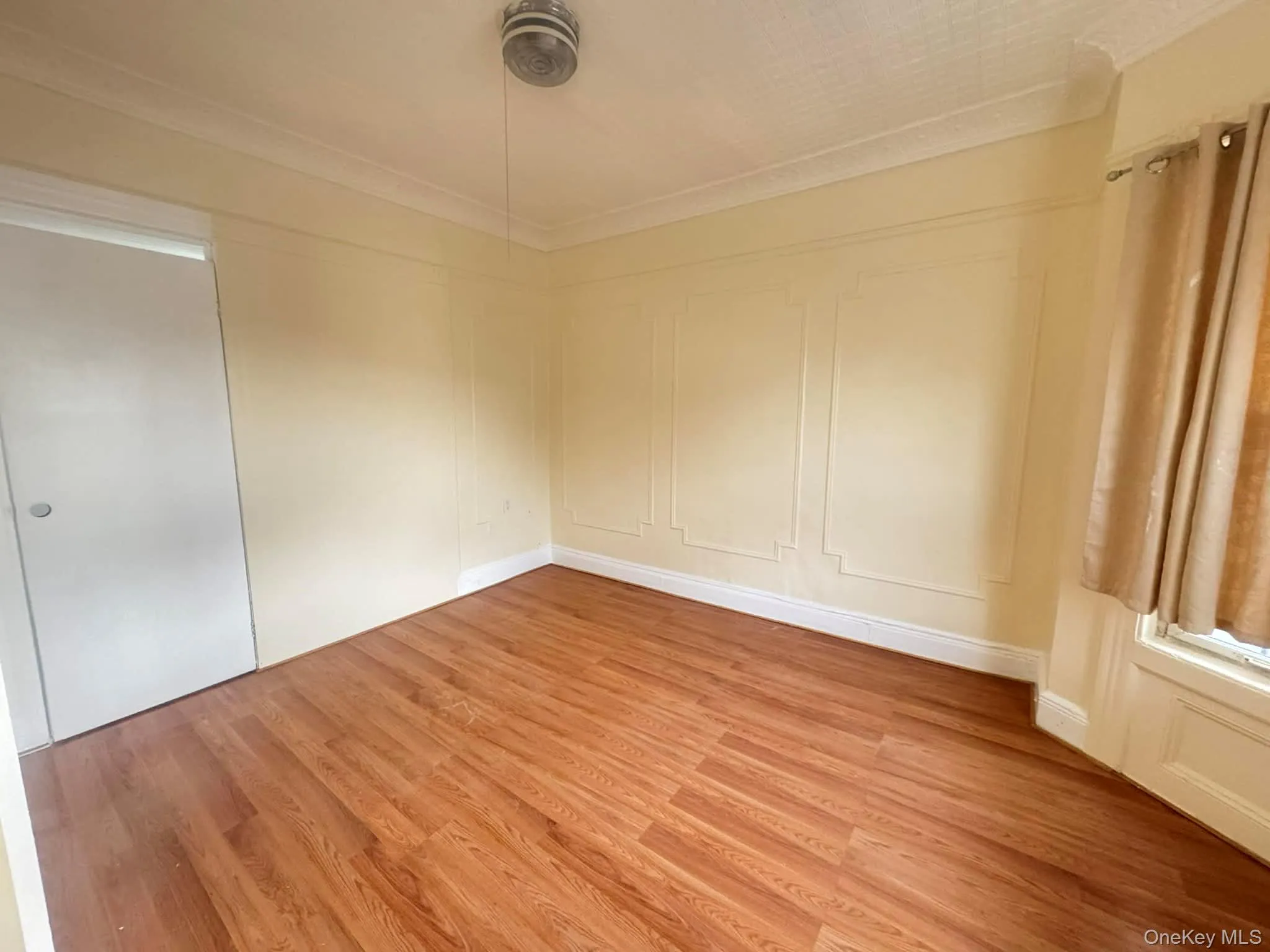 Empty room with a decorative wall, wood finished floors, and ornamental molding Empty room with a decorative wall, wood finished floors, and ornamental molding