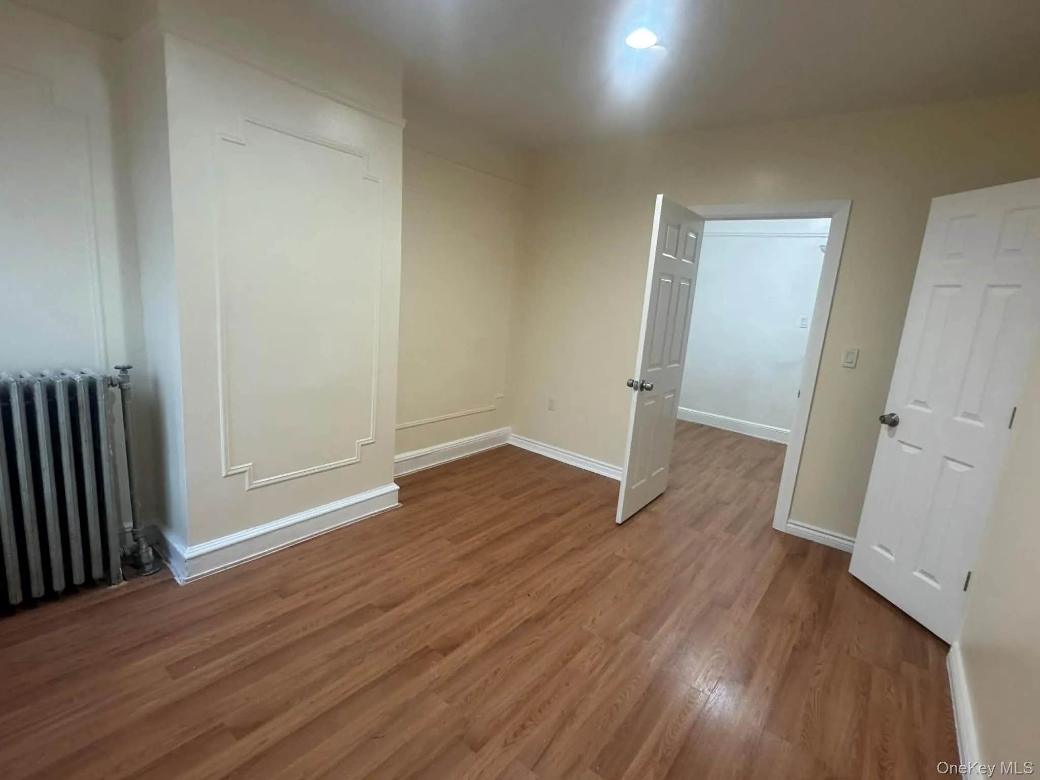 Unfurnished bedroom with radiator and dark wood-type flooring Unfurnished bedroom with radiator and dark wood-type flooring