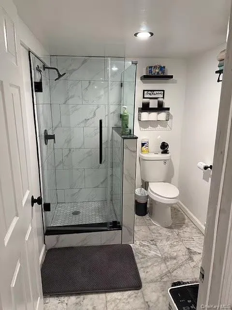 Bathroom with a marble finish shower and light marble finish floors Bathroom with a marble finish shower and light marble finish floors