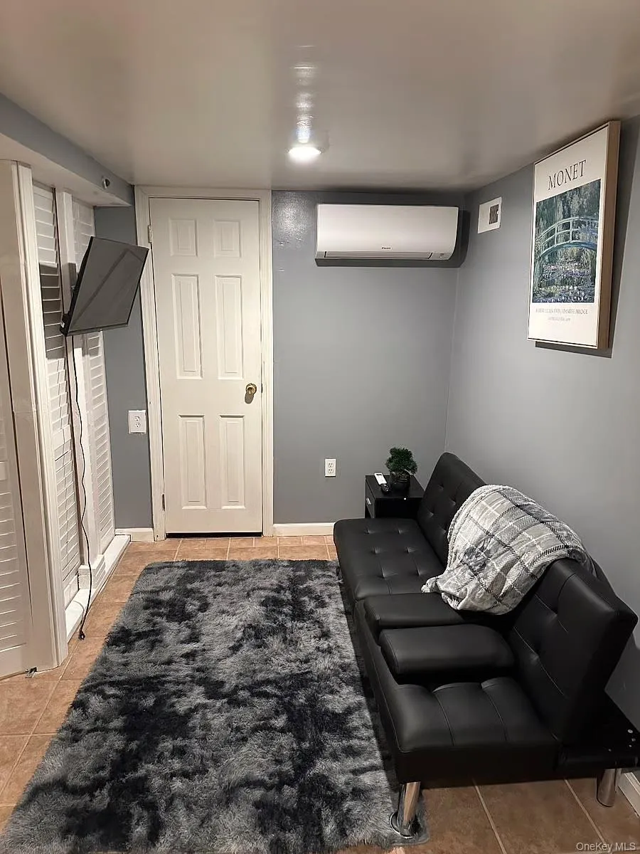 Living area with light tile patterned floors and a wall mounted AC Living area with light tile patterned floors and a wall mounted AC