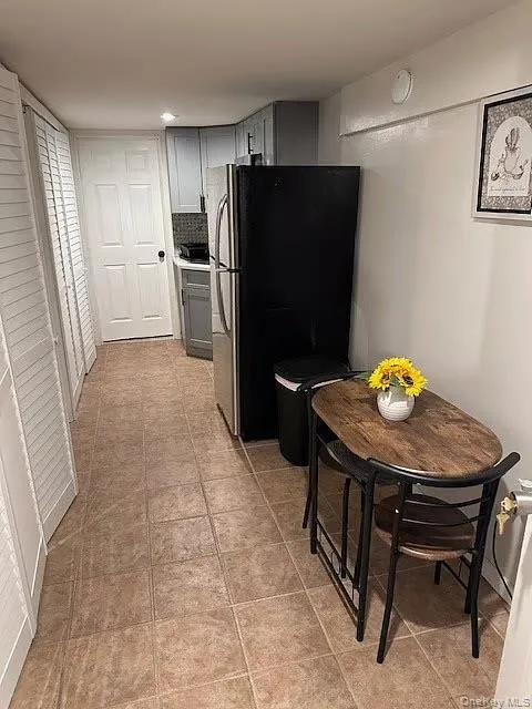 Kitchen featuring freestanding refrigerator, gray cabinetry, and light tile patterned floors Kitchen featuring freestanding refrigerator, gray cabinetry, and light tile patterned floors