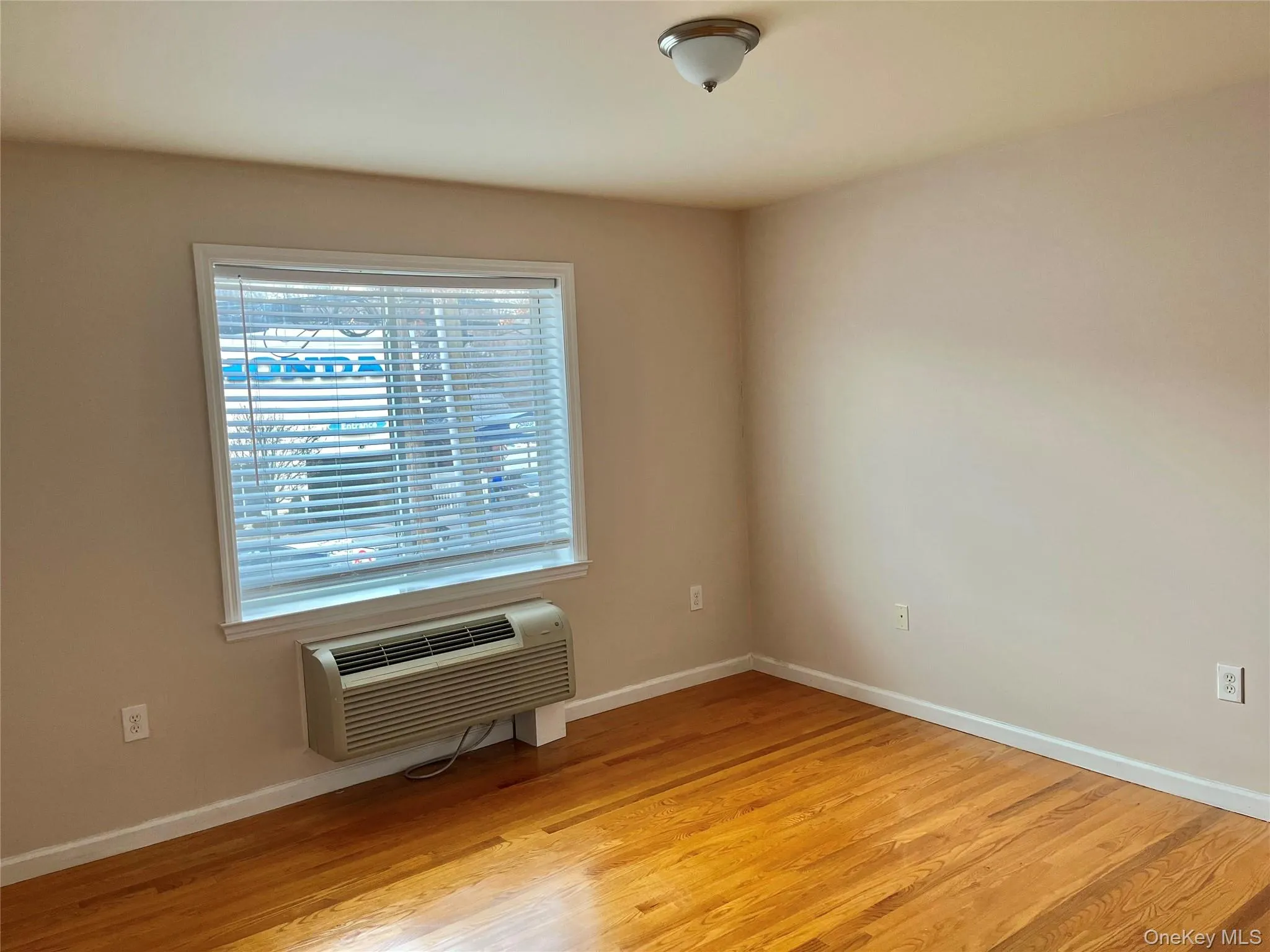 Spare room featuring light wood-style floors and a wall mounted air conditioner Spare room featuring light wood-style floors and a wall mounted air conditioner