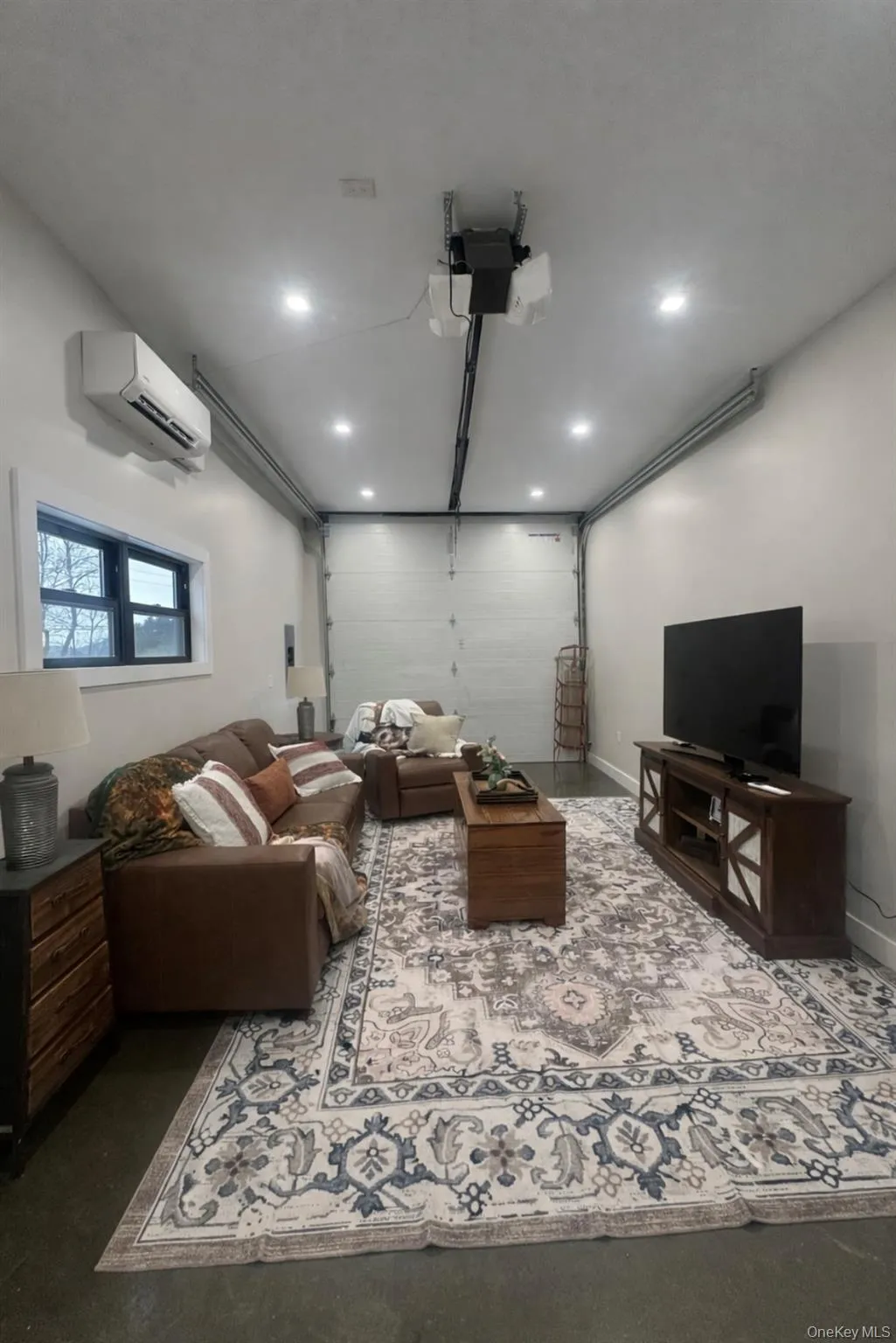 Home theater with a garage, finished concrete floors, a wall unit AC, and recessed lighting Home theater with a garage, finished concrete floors, a wall unit AC, and recessed lighting