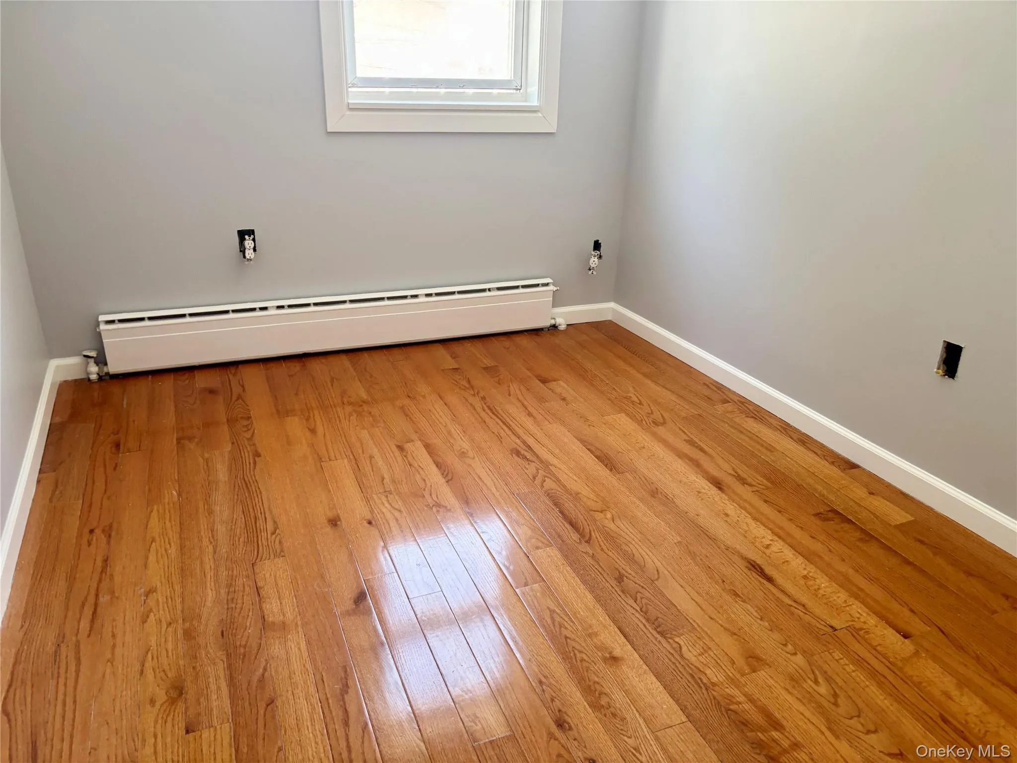 Empty room featuring baseboard heating and light wood-style flooring Empty room featuring baseboard heating and light wood-style flooring