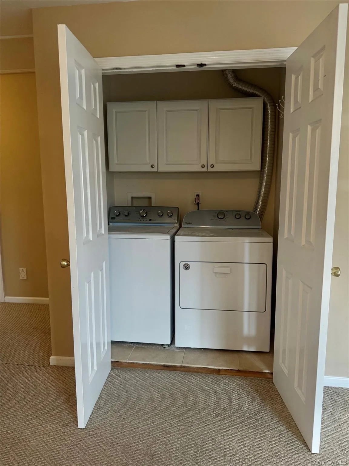 Washroom with light colored carpet, cabinet space, and washer and clothes dryer Washroom with light colored carpet, cabinet space, and washer and clothes dryer